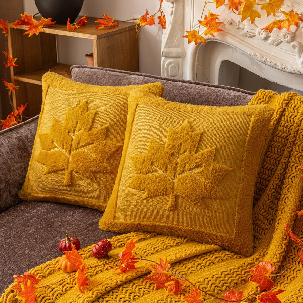Two mustard maple leaf pillow covers on a sofa