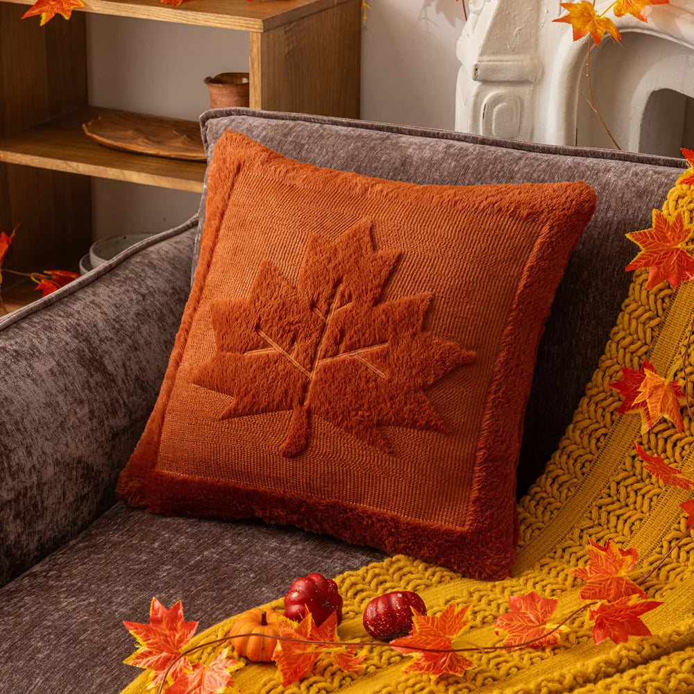 Rust maple leaf pillow cover on a gray sofa with a mustard throw