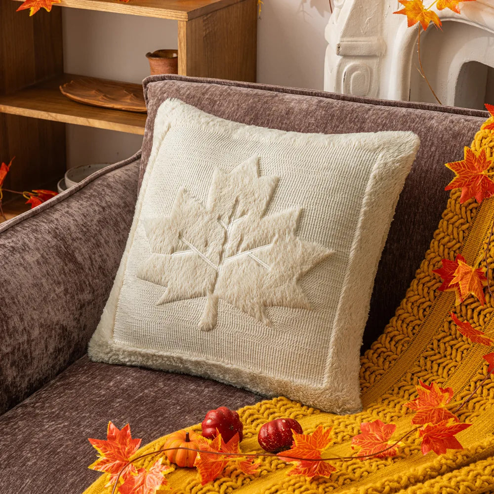 Cream maple leaf pillow cover on a gray sofa with a mustard throw