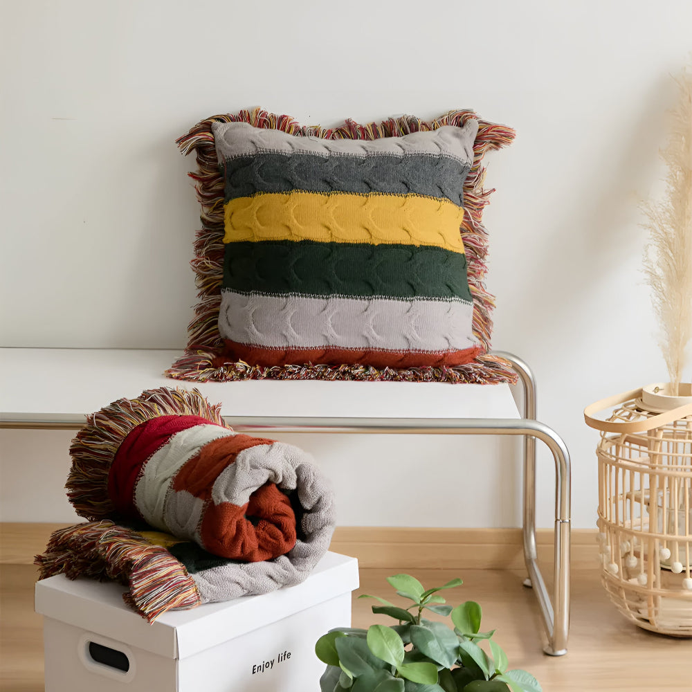 Striped cable knit cushion on a bench with a rolled one below
