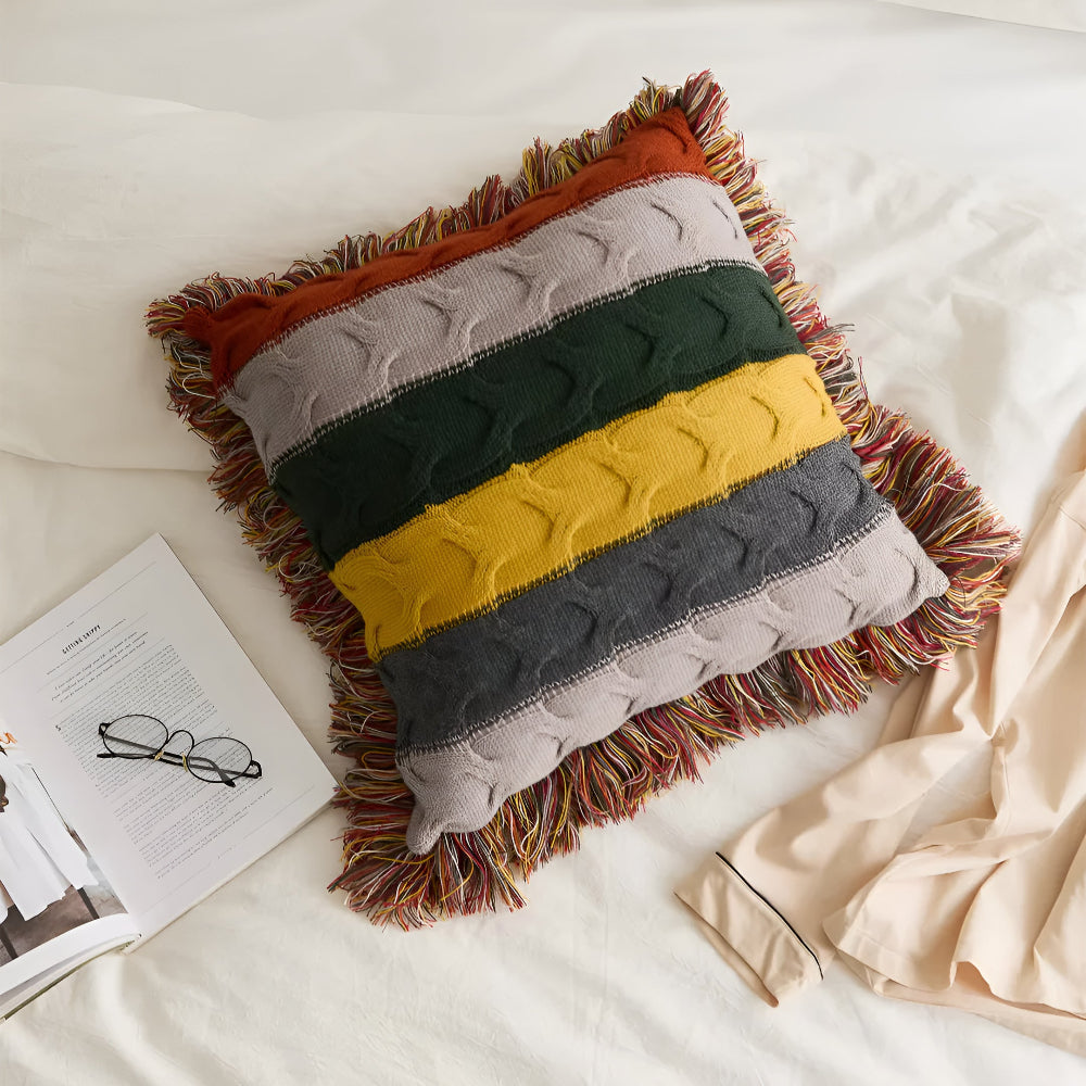 Striped cable knit cushion laid on a bed