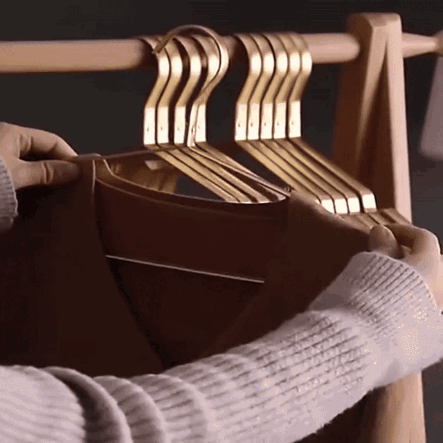 Hanging tops on aluminum hangers on a wooden rack