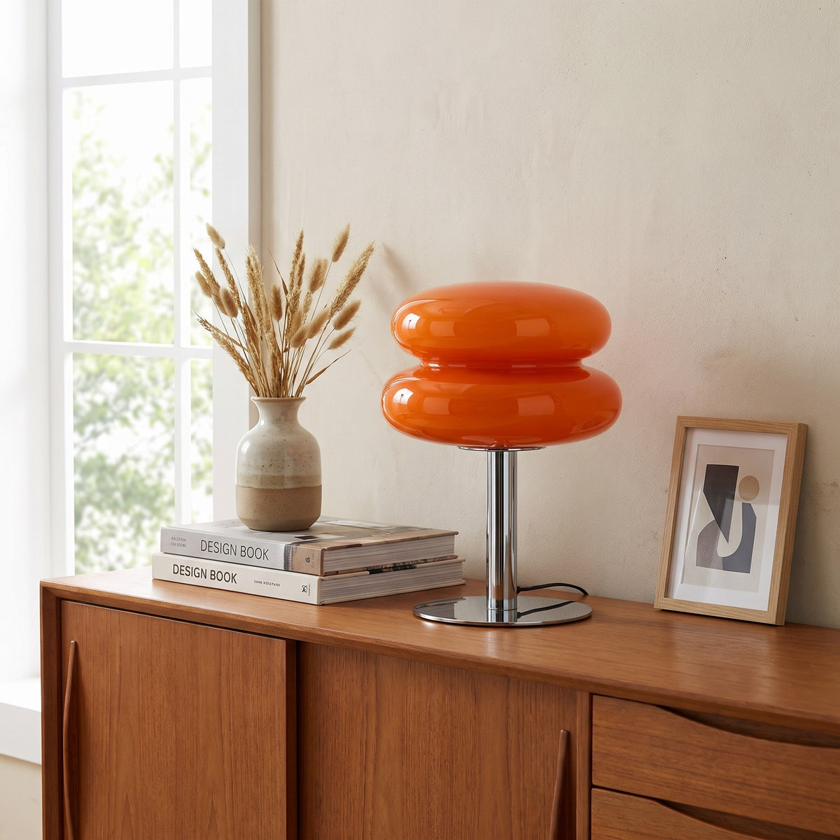 Annika glass table lamp in orange on a teak sideboard by a window