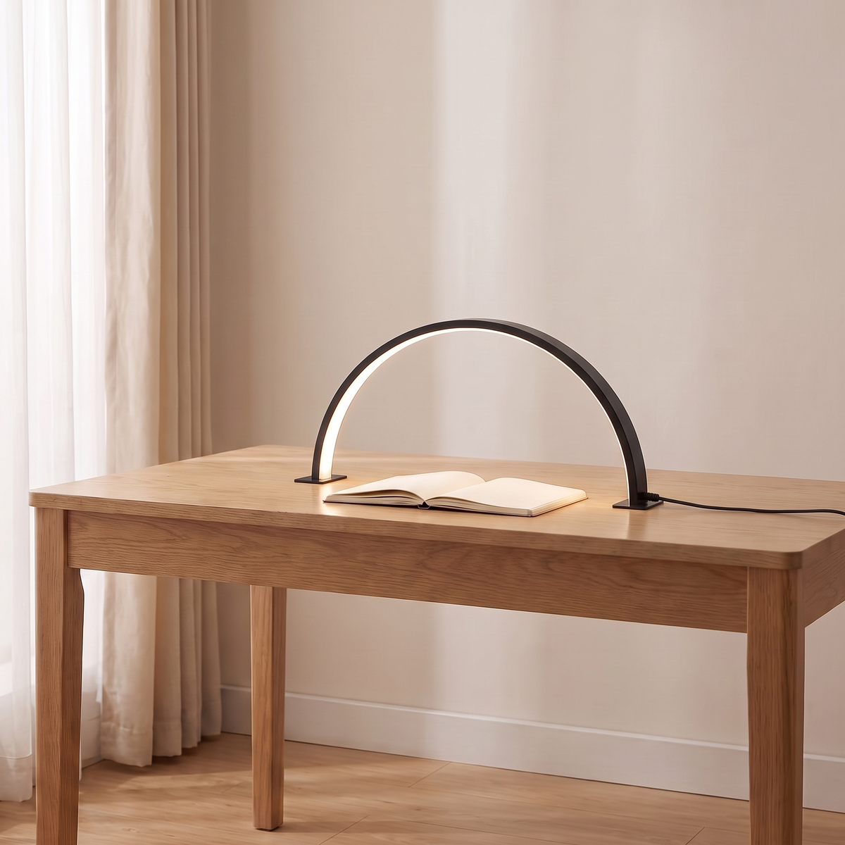 Bryn half moon desk lamp in black lit on a light oak desk