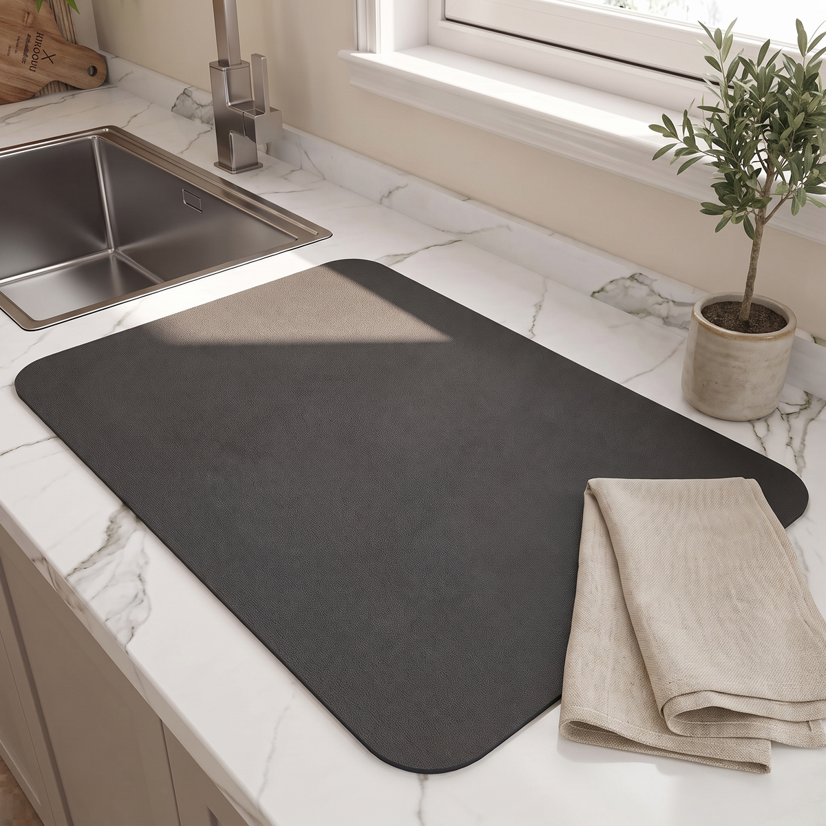 Black dish drying mat lying flat on a marble counter by the sink