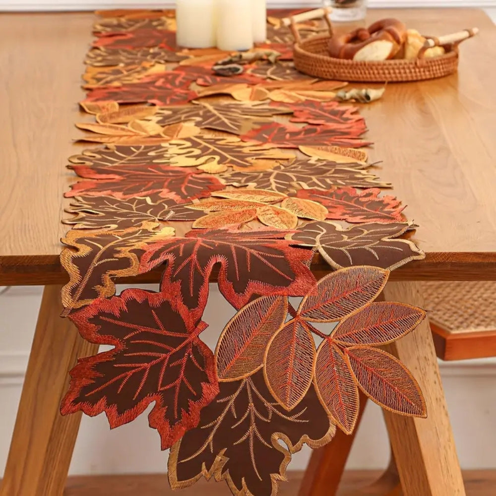 Embroidered leaf table runner on an oak dining table with candles and a bread basket