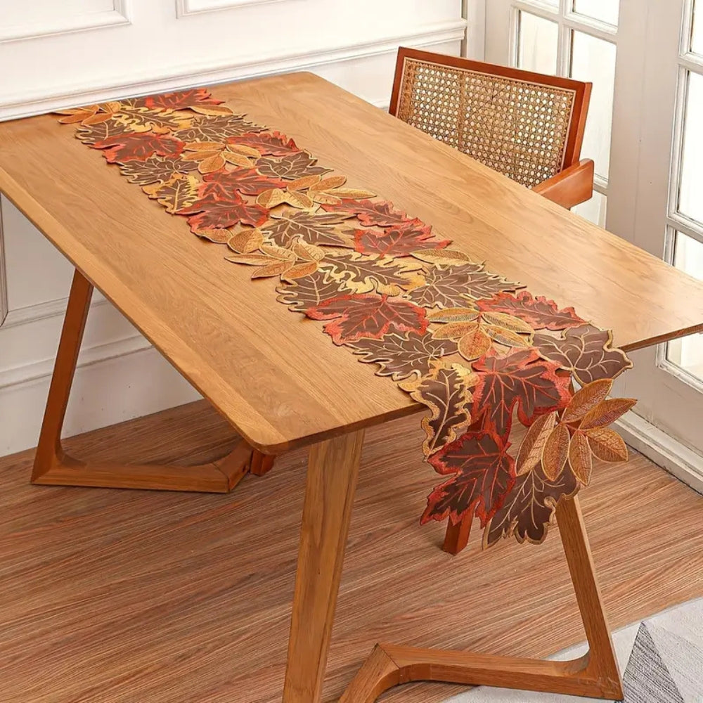 Embroidered leaf runner hanging over the end of a wood table
