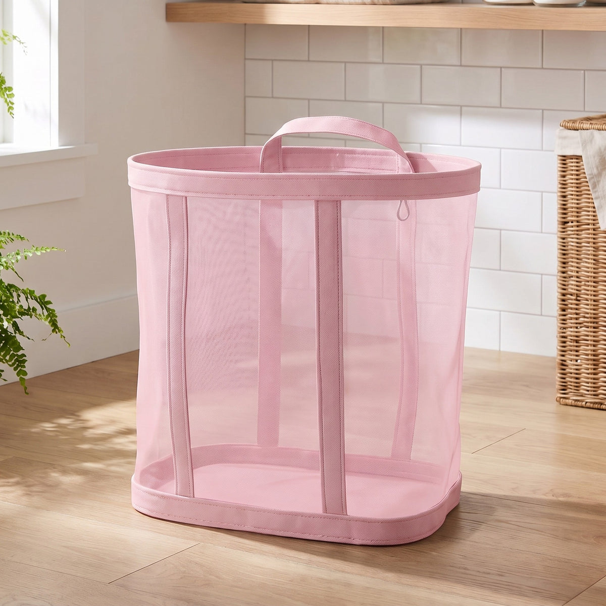 Pink mesh laundry basket standing on a wood floor in a laundry room