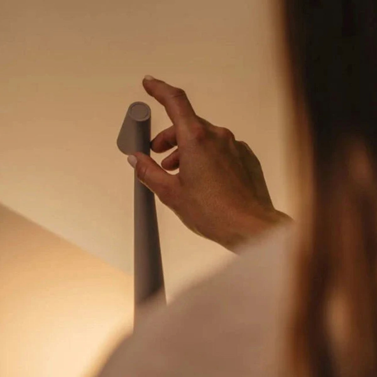 A hand tapping the touch sensor on top of the Iben table lamp