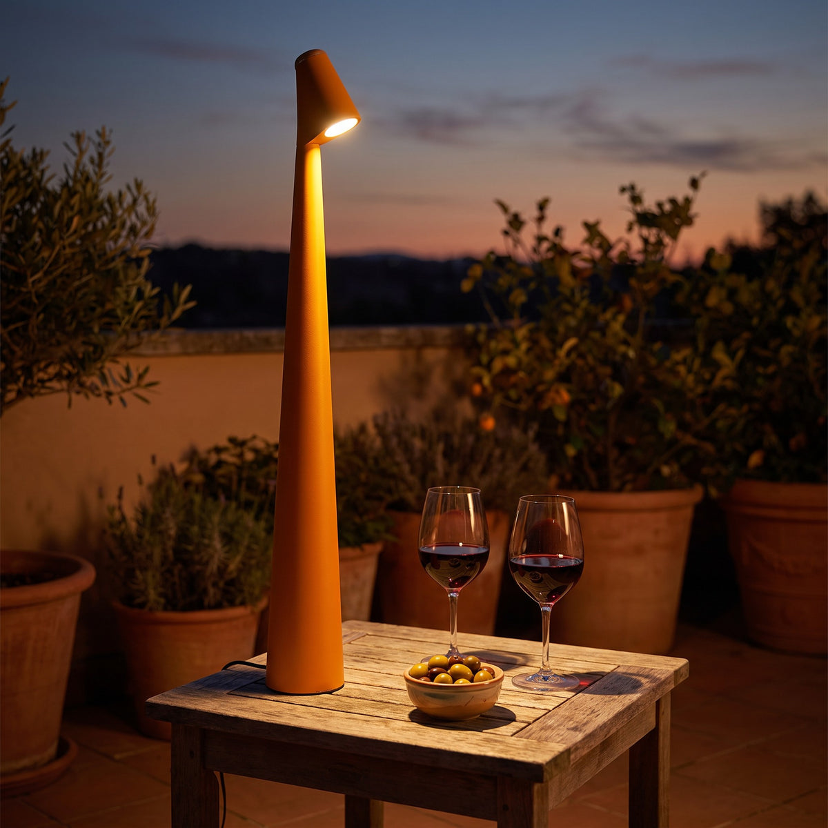 Iben table lamp in orange on a patio table at dusk