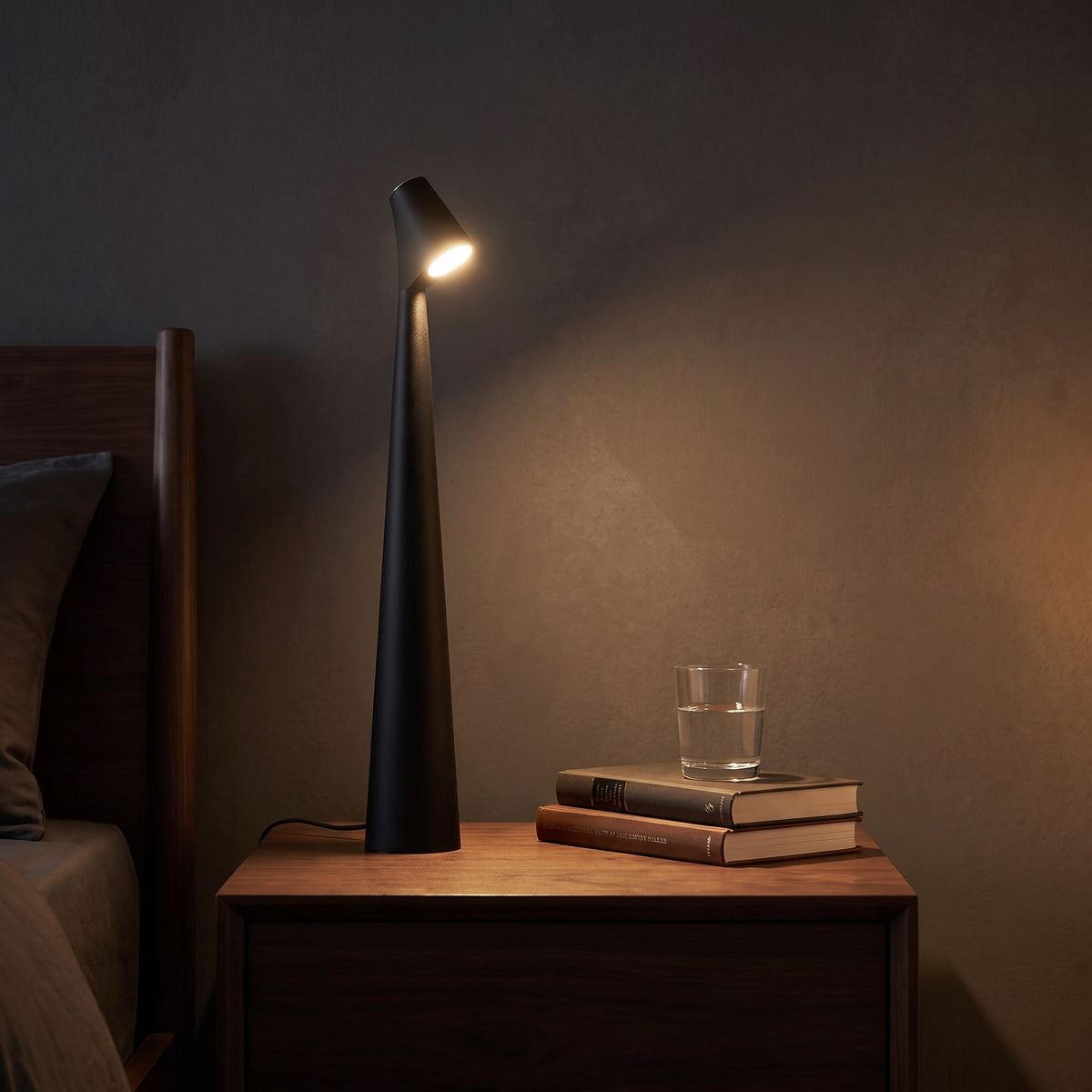 Iben table lamp in black on a bedside table at night