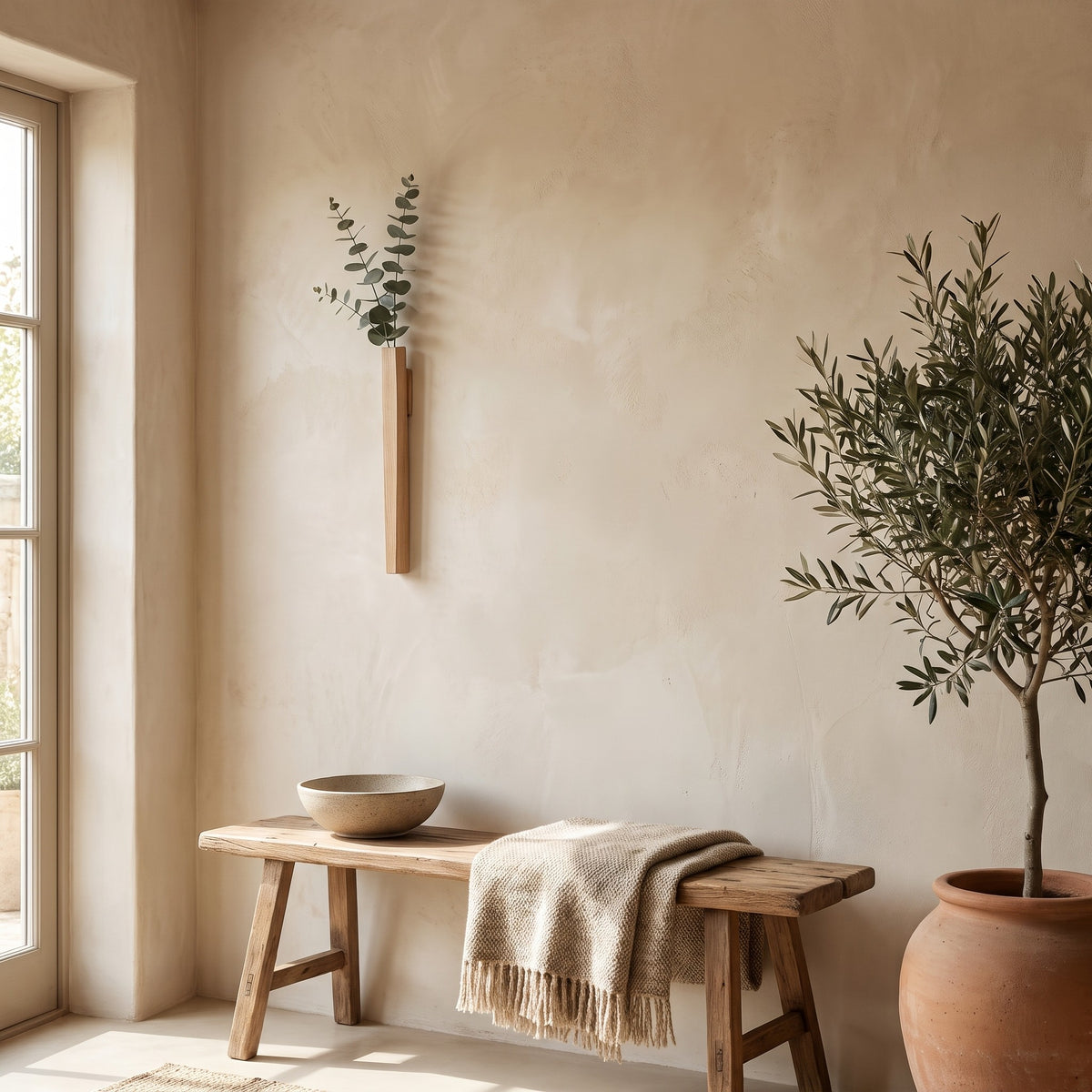 Idun wall vase holding eucalyptus beside an olive tree