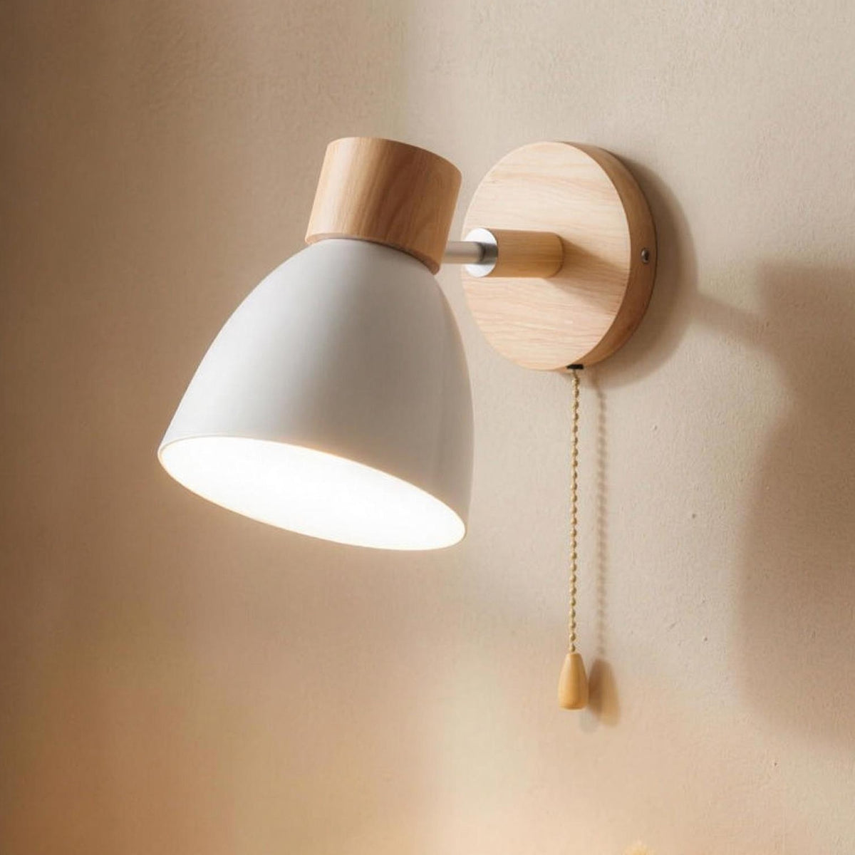 Juni wall sconce, white cone shade, wood plate and pull chain, over a nightstand