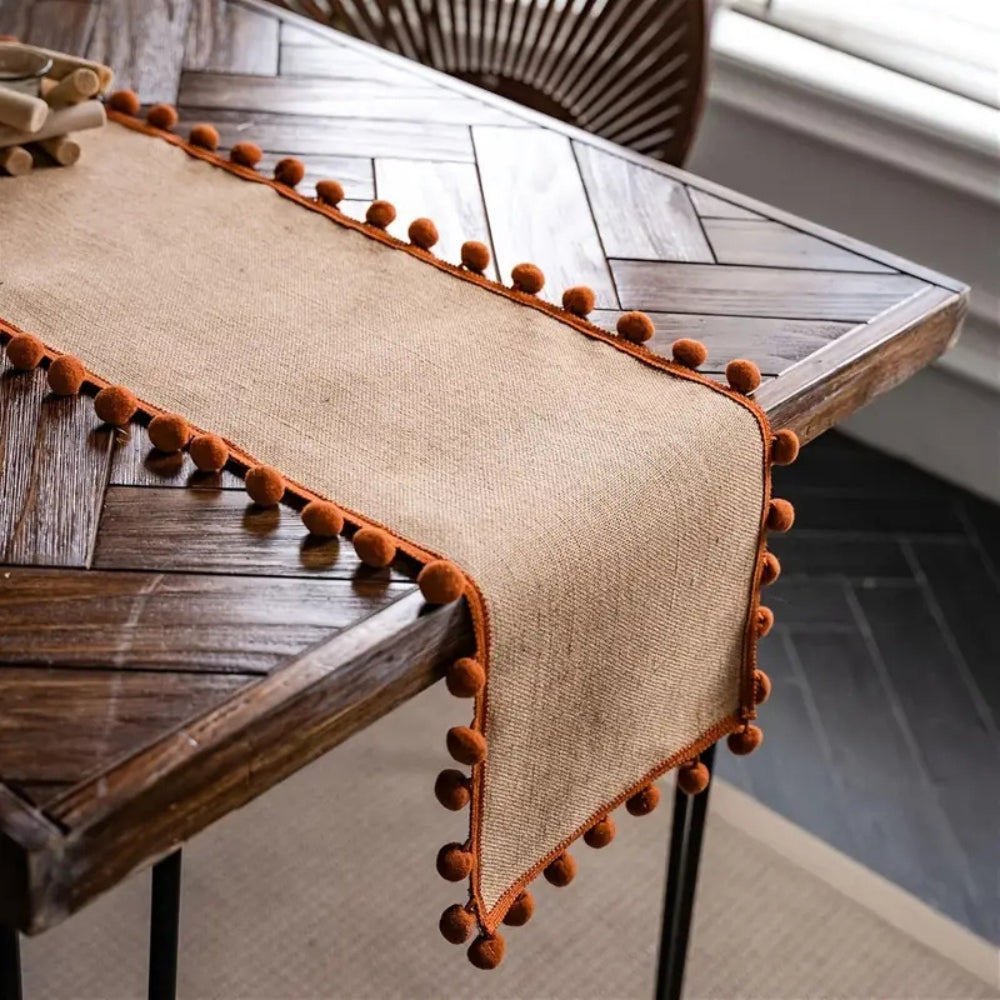 Jute pom pom runner on a herringbone wood table