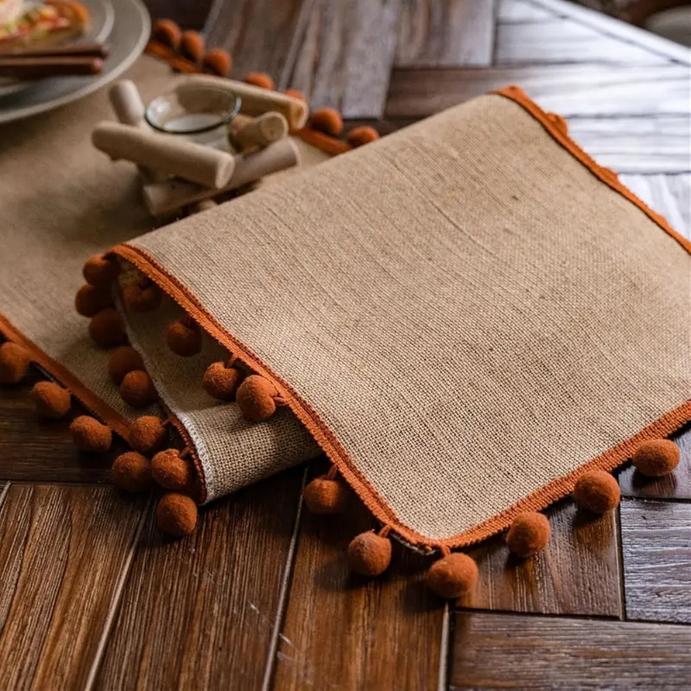 Jute pom pom runner folded at the end of a wood table