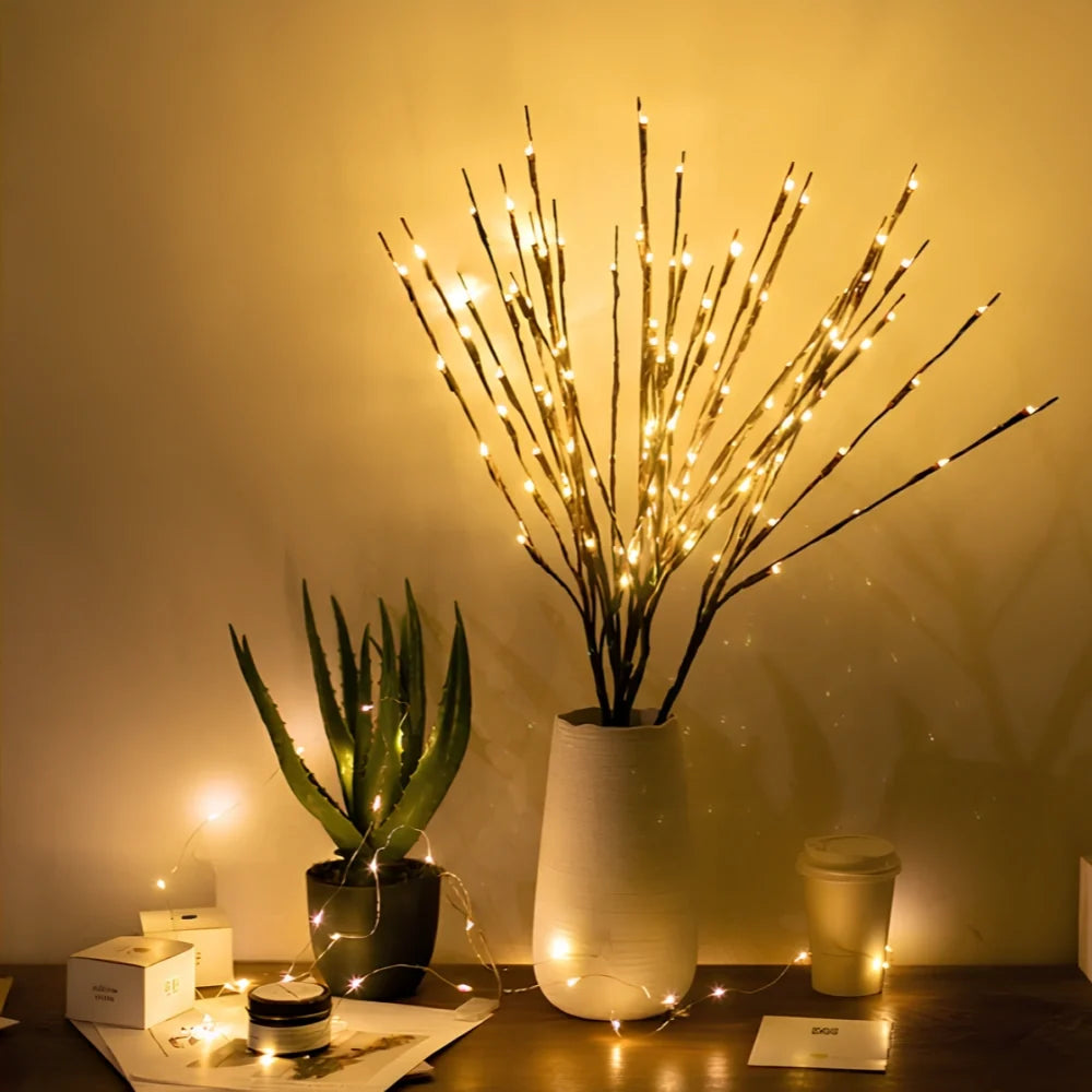 Lighted willow branches in a white vase on a console