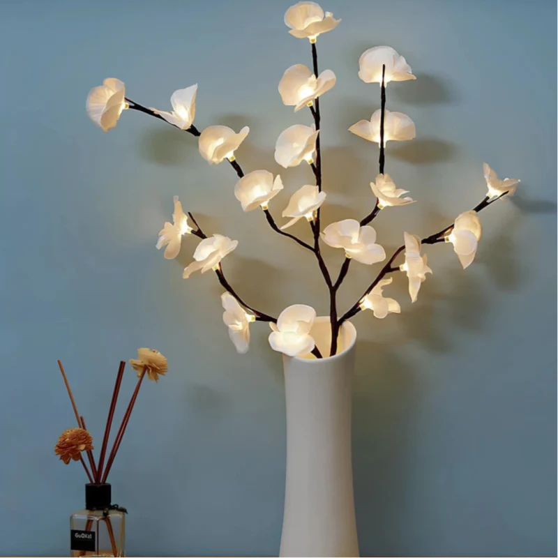 Lighted white orchid branches in a white vase