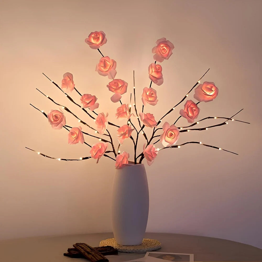 Lighted branches with pink roses in a vase