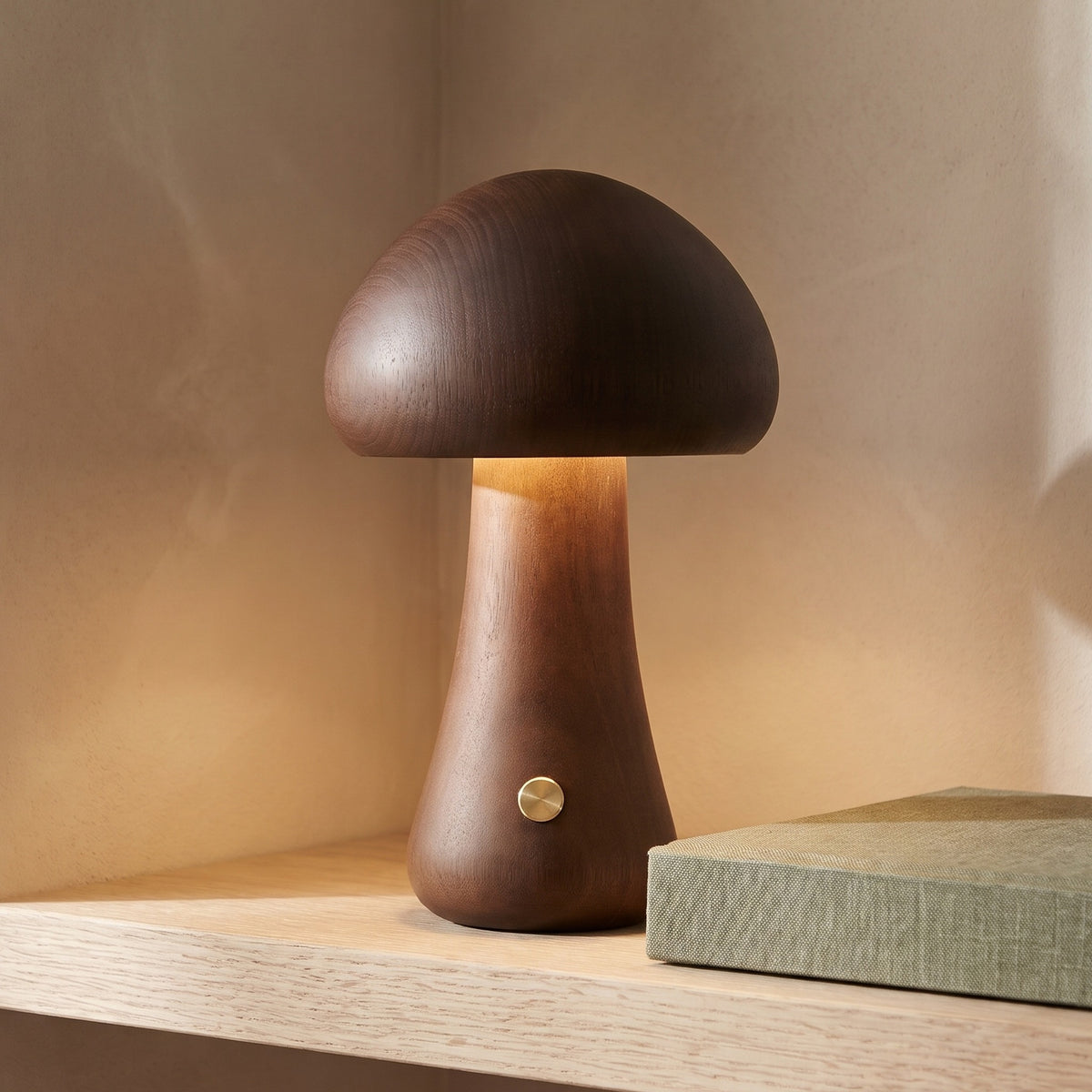 Maila mushroom table lamp, Style A in walnut, lit on a pale oak shelf against a warm plaster wall