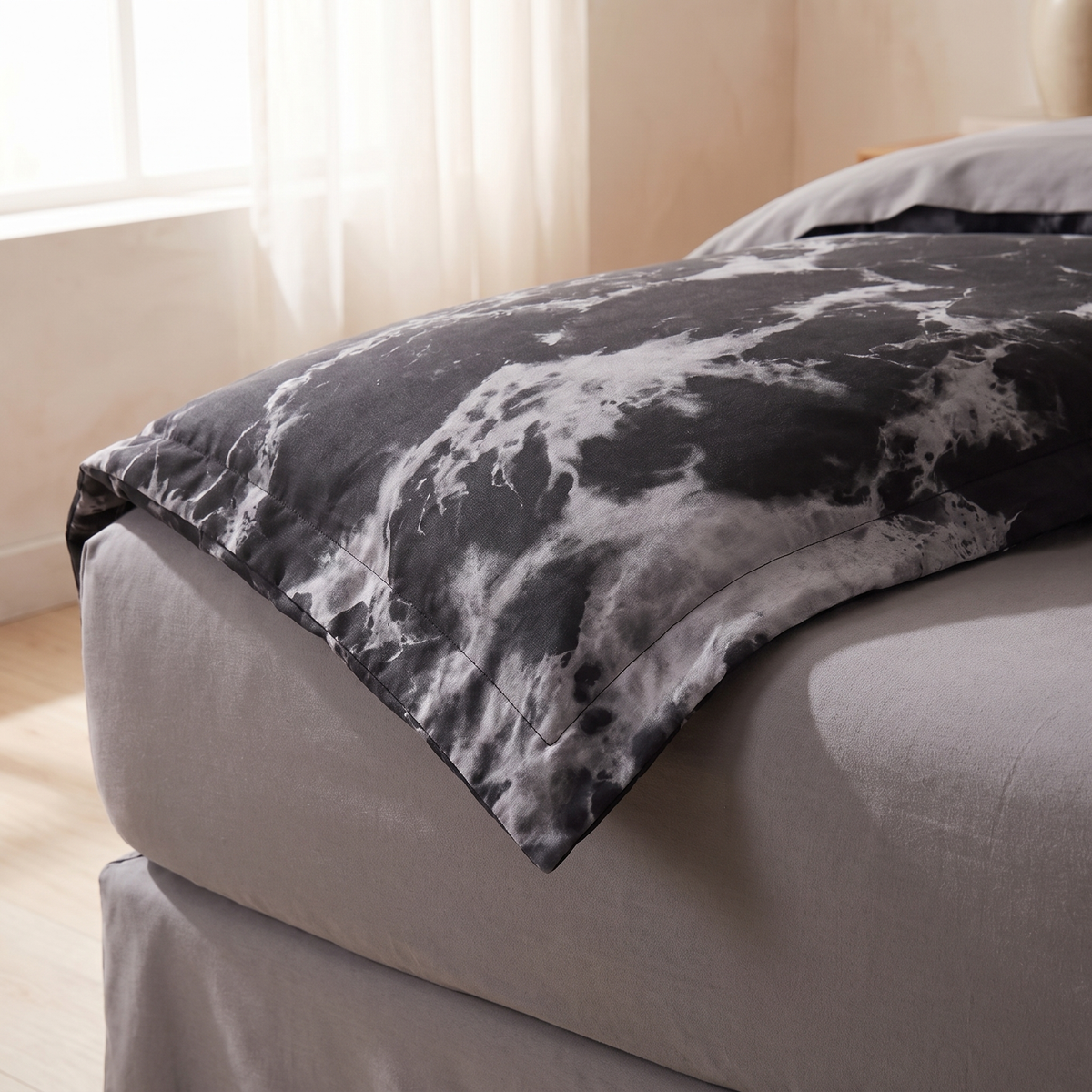 Corner of the black marble duvet cover folded back on a bed