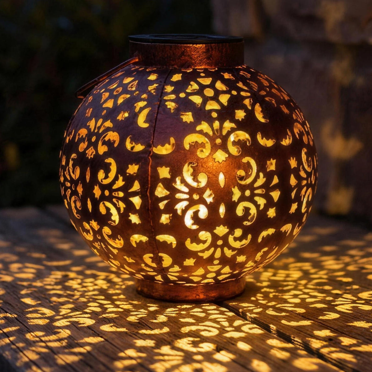 Mette solar lantern casting its cut out pattern across a garden bench at night
