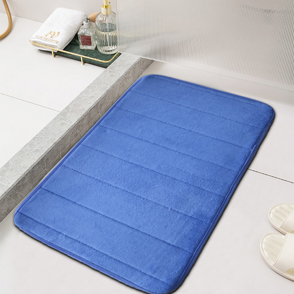 Blue microfiber bath mat with ribbed channels beside a white bathtub
