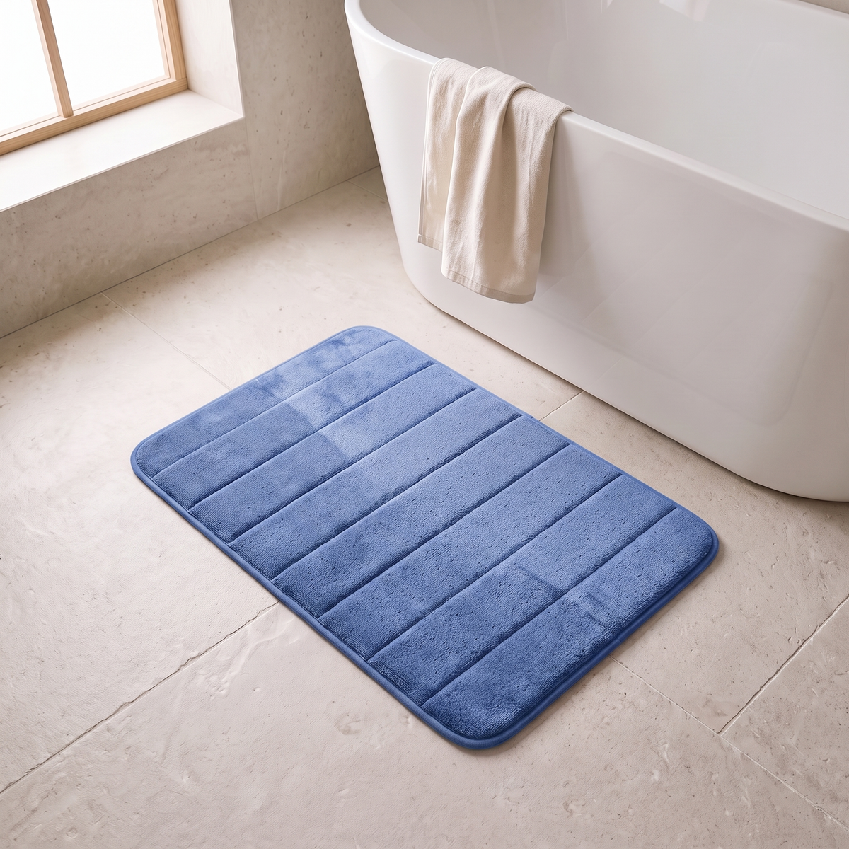Microfiber bath mat in blue on a stone floor beside a bathtub