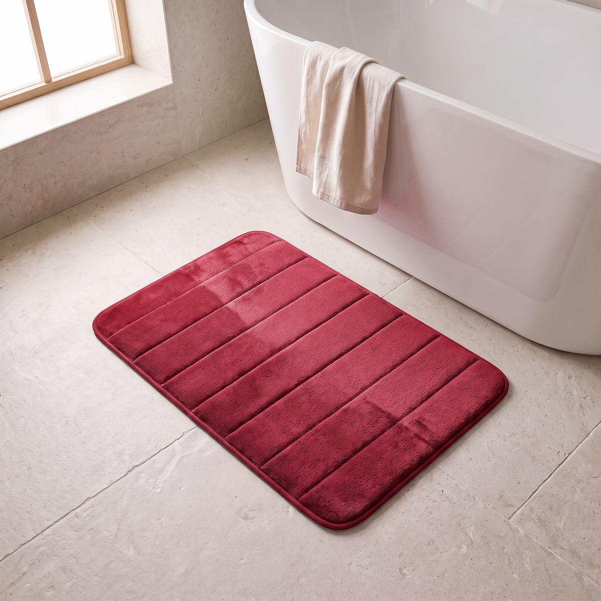 Microfiber bath mat in red on a stone floor beside a bathtub