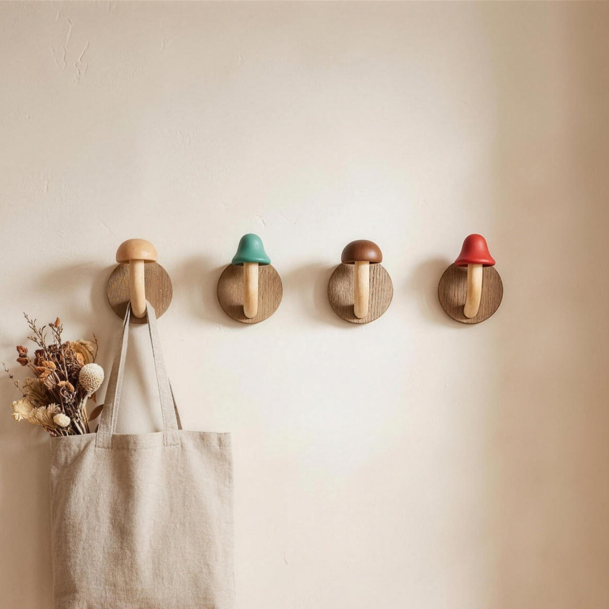 Four mushroom wall hooks with colored caps on a wall