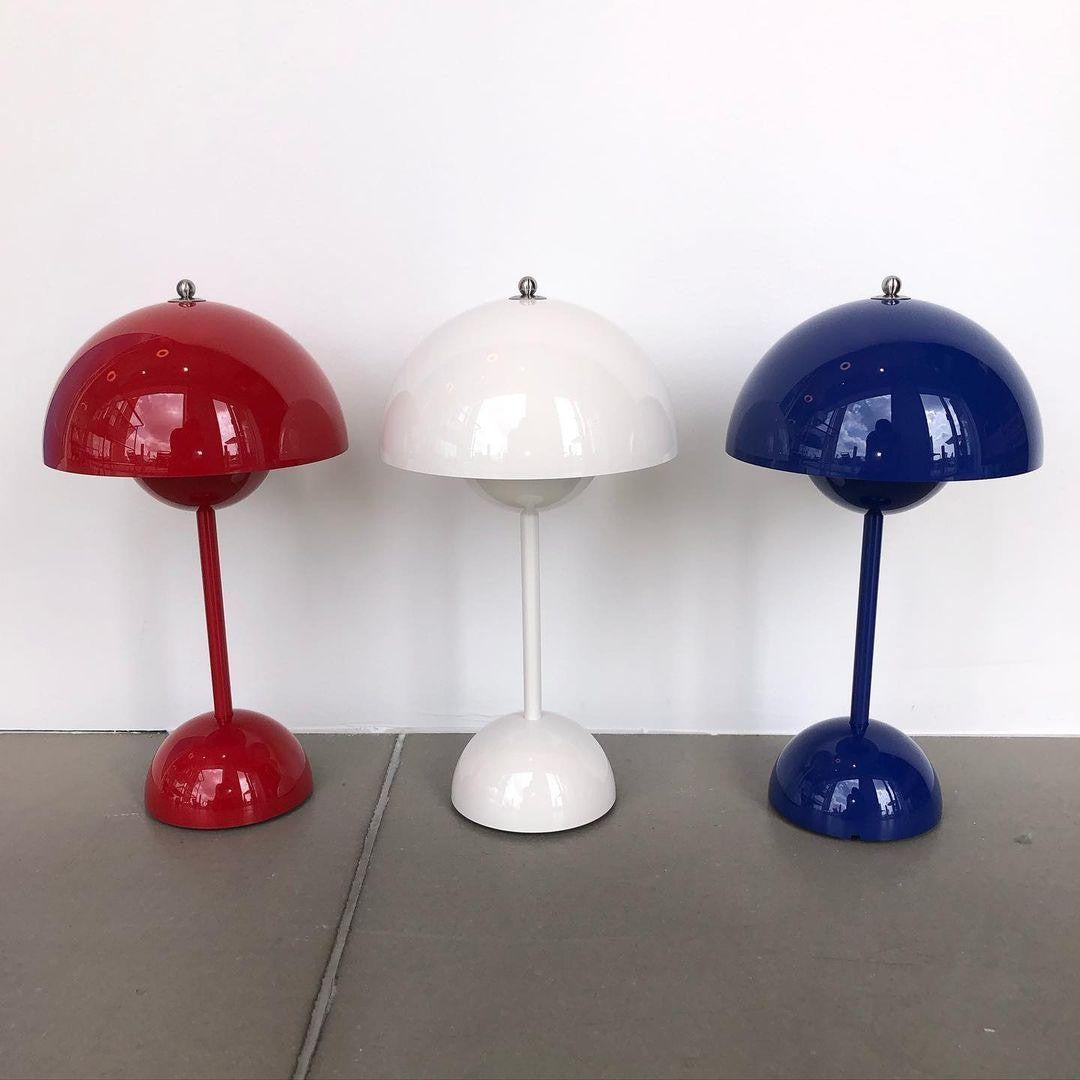 Three Oona table lamps in red, white and dark blue side by side on a table