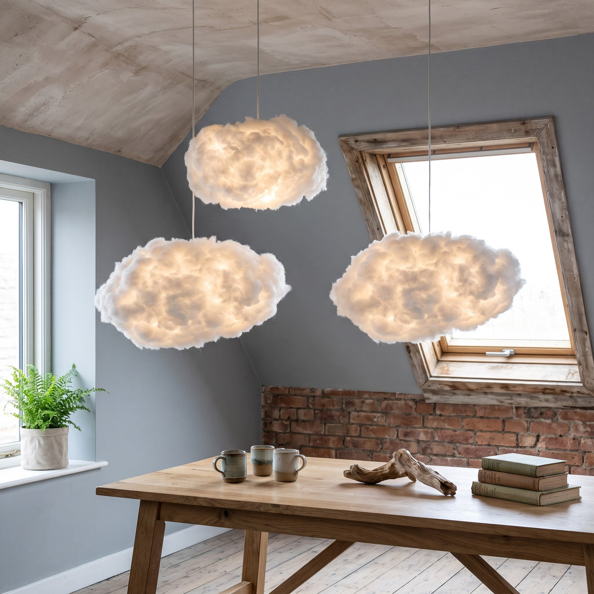 Three Petra cloud pendant lights glowing over a wooden table