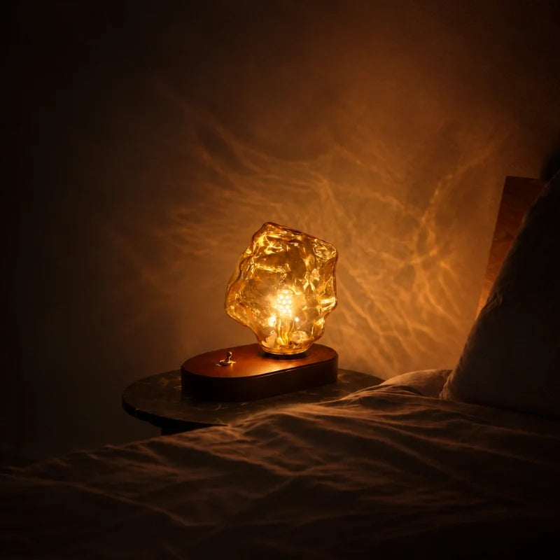 Ribe amber glass table lamp lit on a dark nightstand