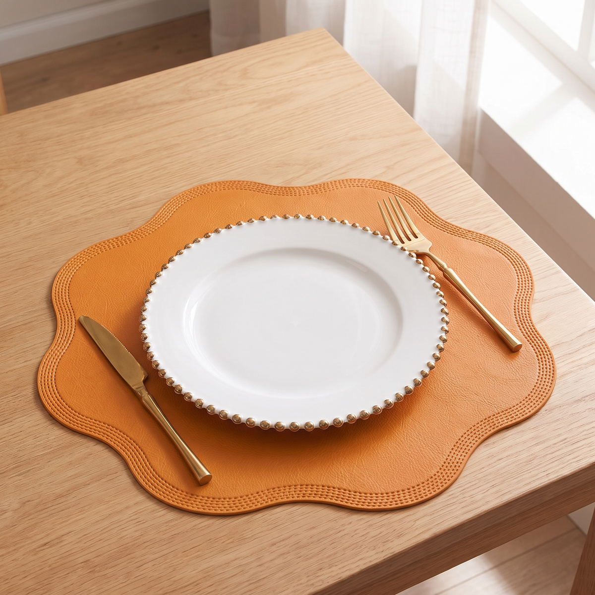 Scalloped placemat in yellow with a white plate and gold cutlery on an oak table