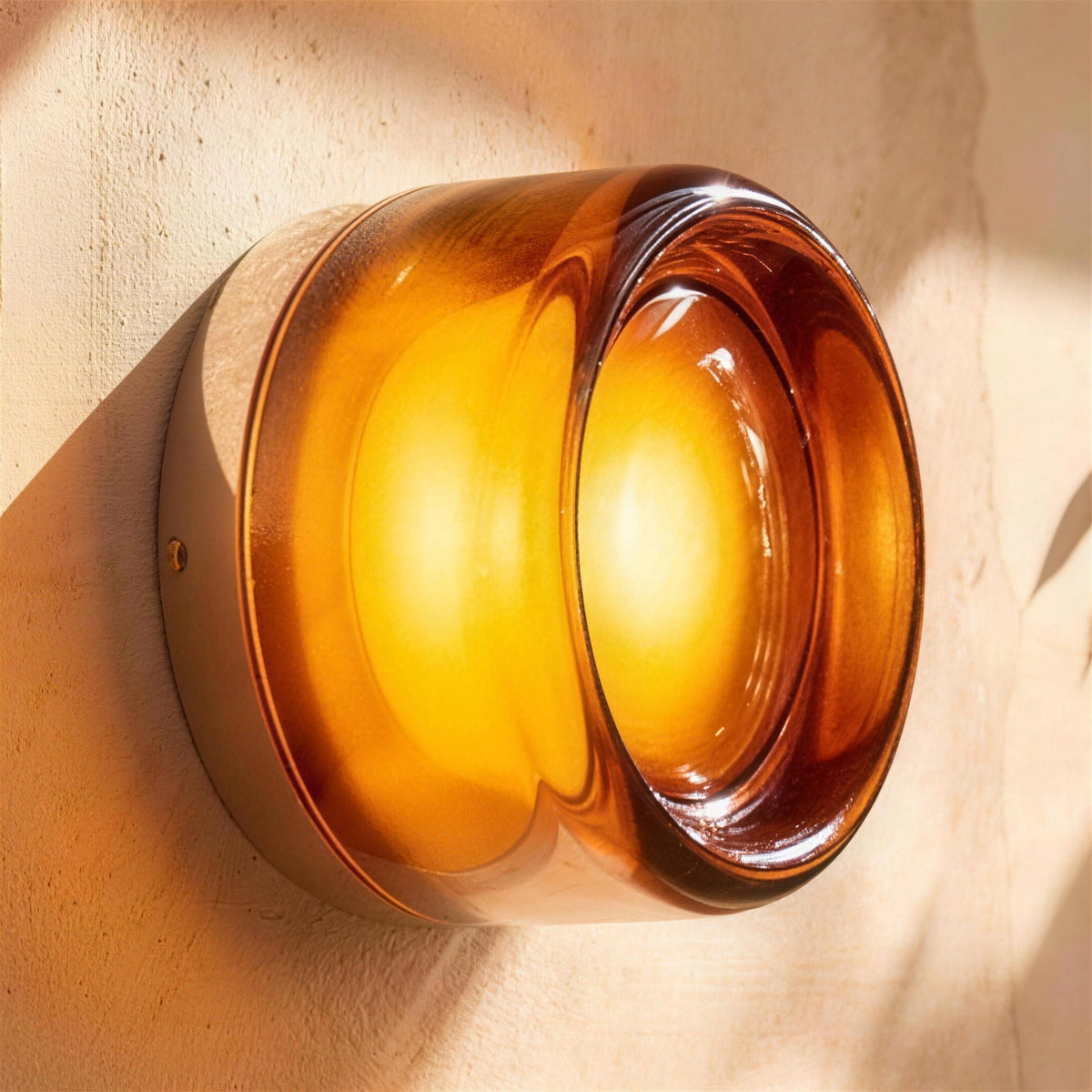 Siv LED wall sconce, amber dimple shade, lit on a plaster wall