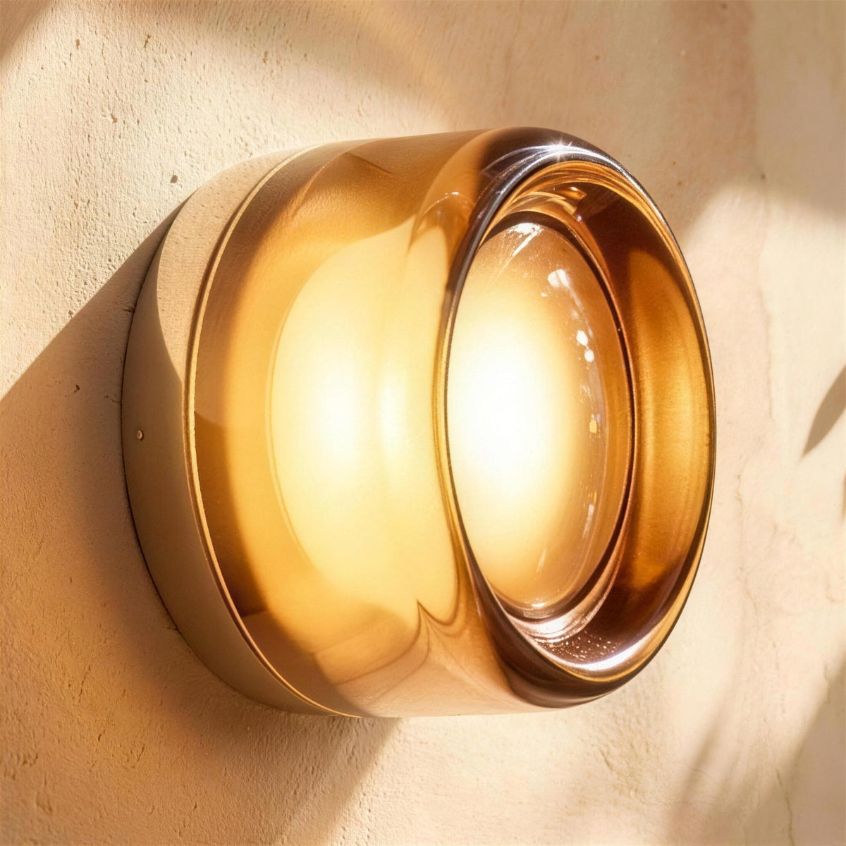 Siv LED wall sconce, smoky gray dimple shade, lit on a plaster wall