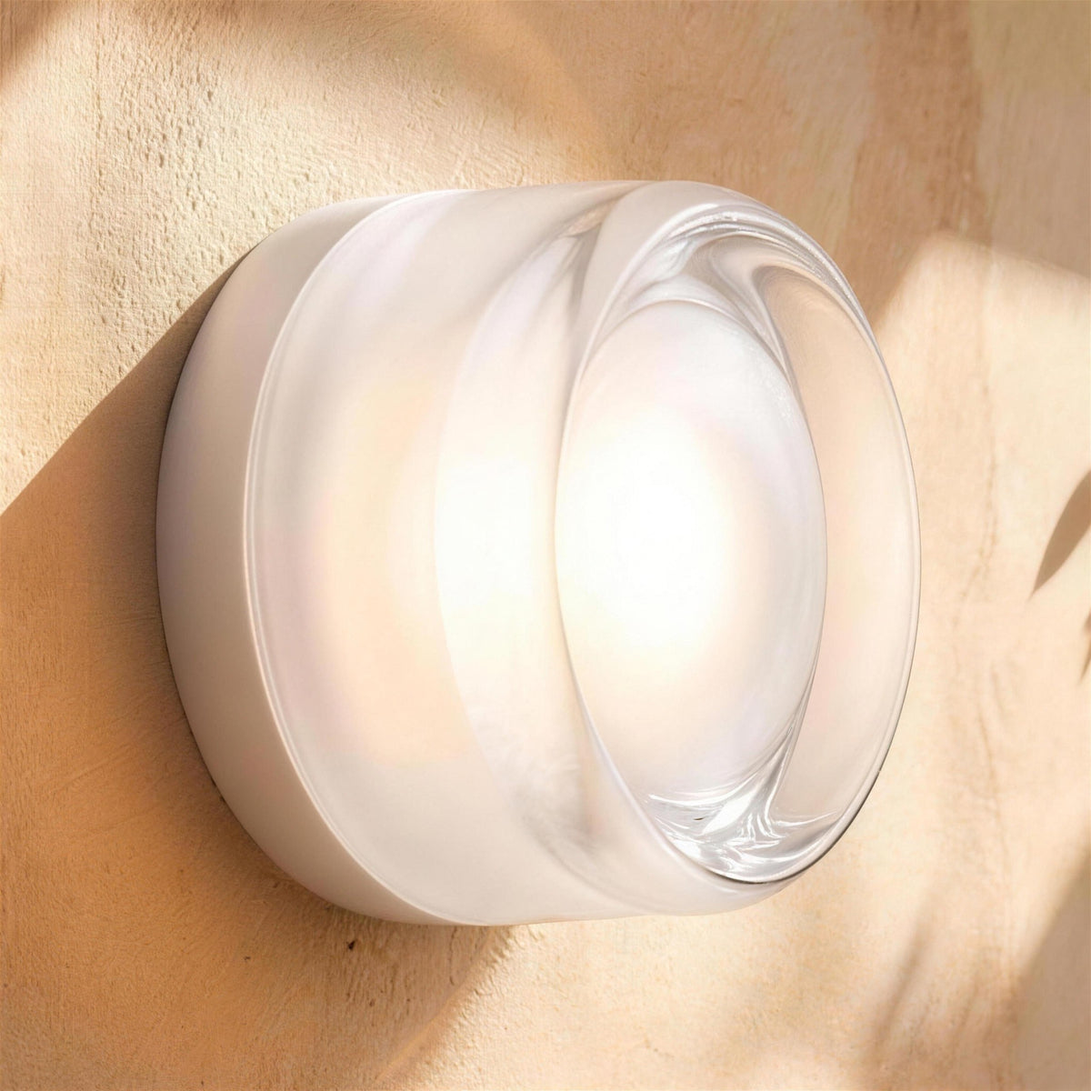 Siv LED wall sconce, white dimple shade, lit on a plaster wall