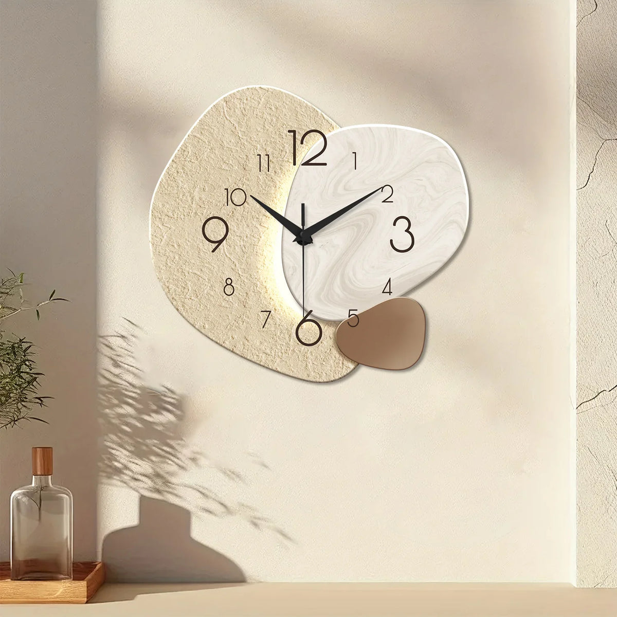 Skien pebble wall clock on a sunlit cream wall above a low shelf with a glass bottle