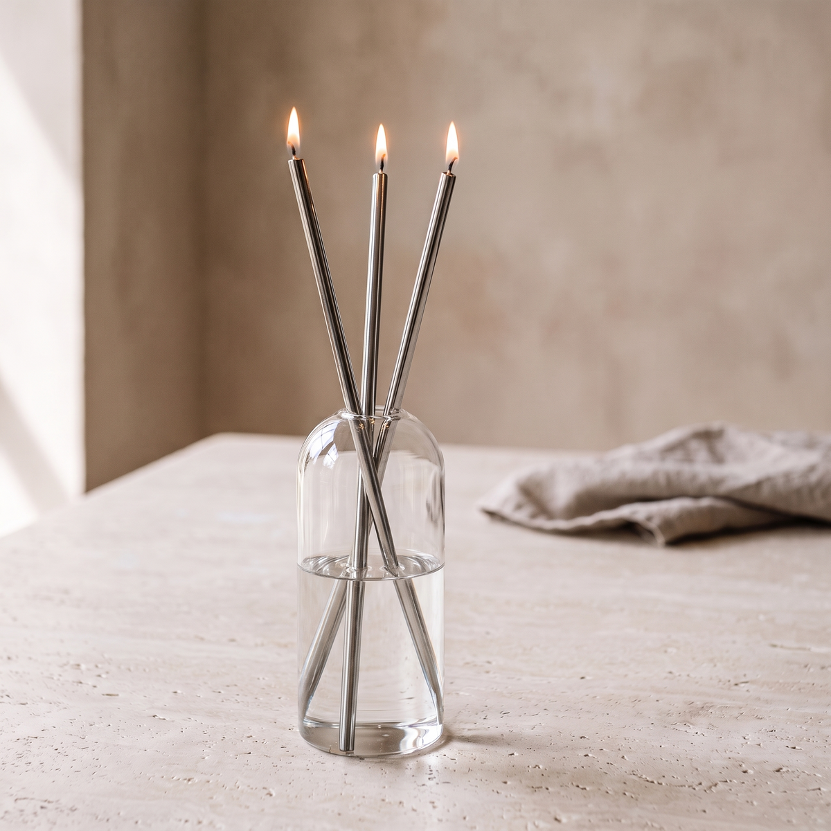 Skive oil candles with silver stems lit on a limestone table