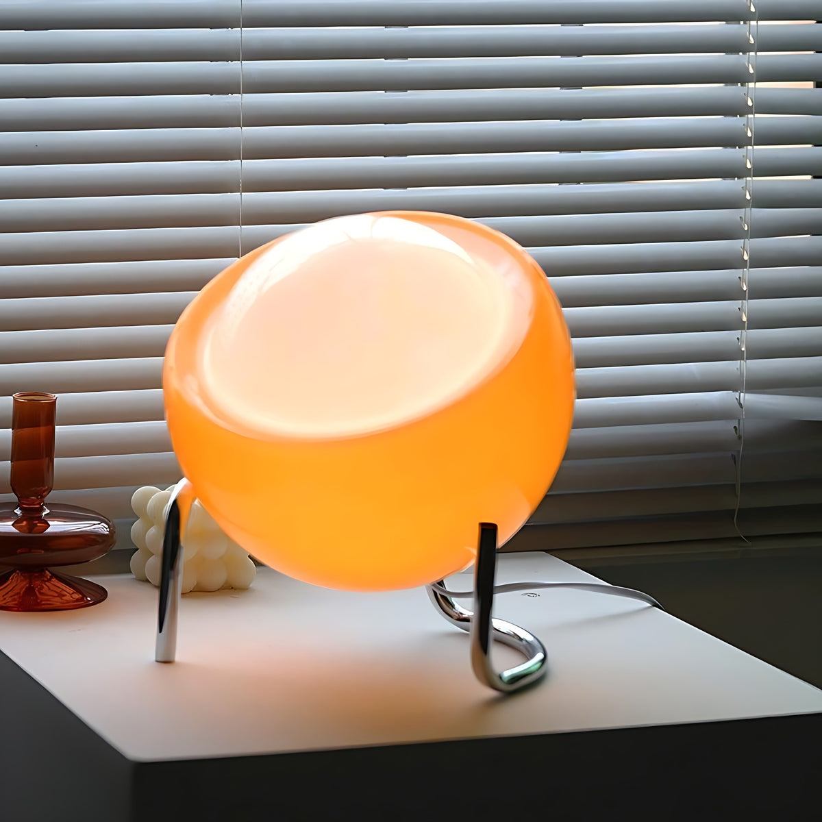 Solveig table lamp on a white side table in front of window blinds