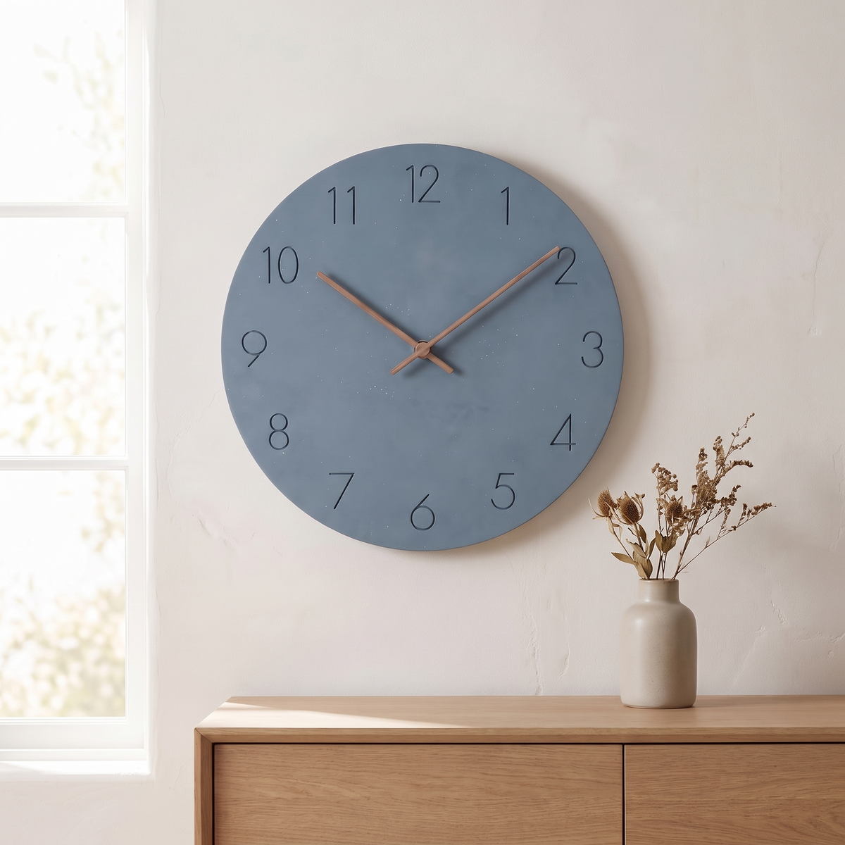 Sten wall clock with a slate blue dial hung above a light oak dresser