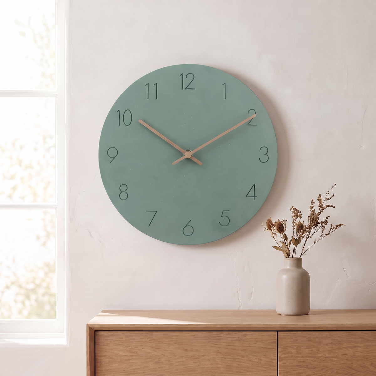 Sten wall clock with a sage green dial on a plaster wall