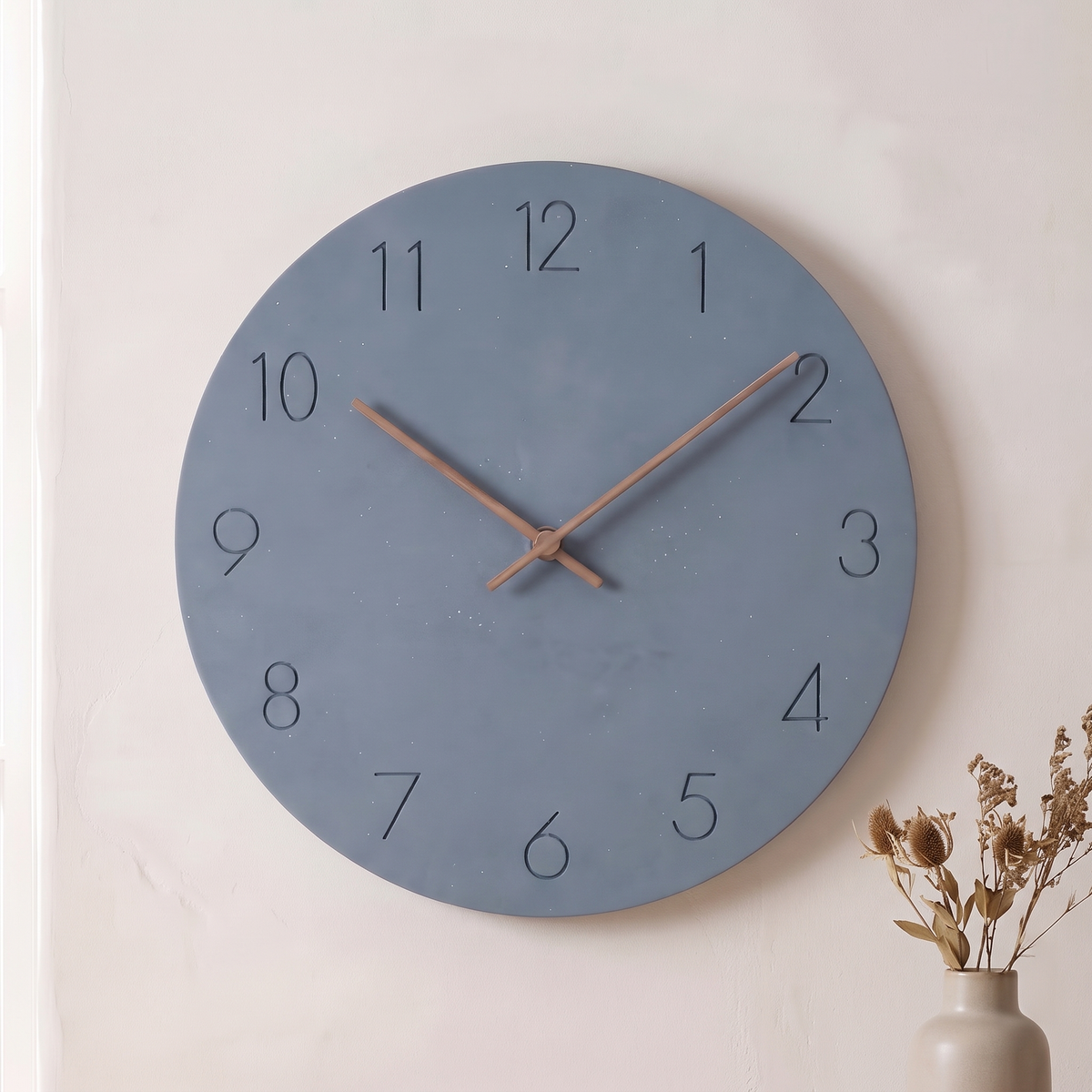 Sten wall clock with a slate blue dial on a plaster wall