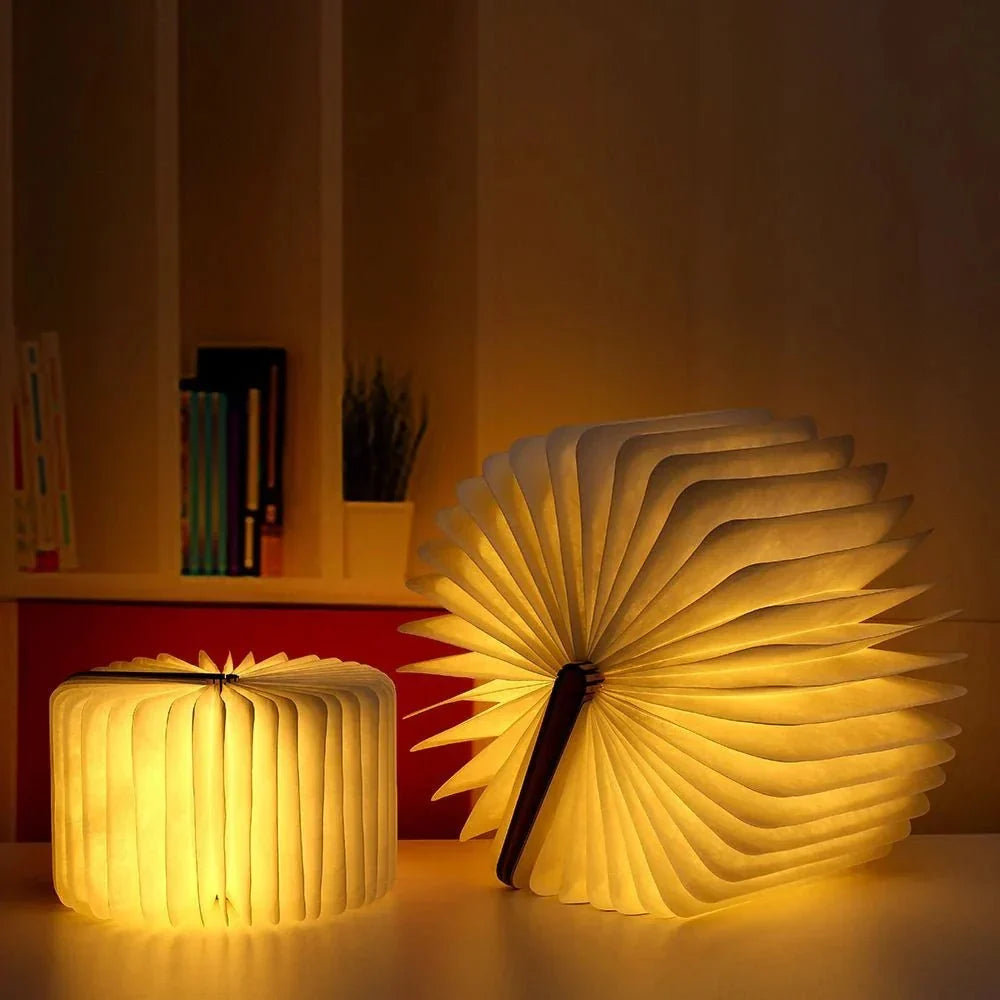 Two Sula book lamps glowing on a shelf, one opened into a fan and one into a drum