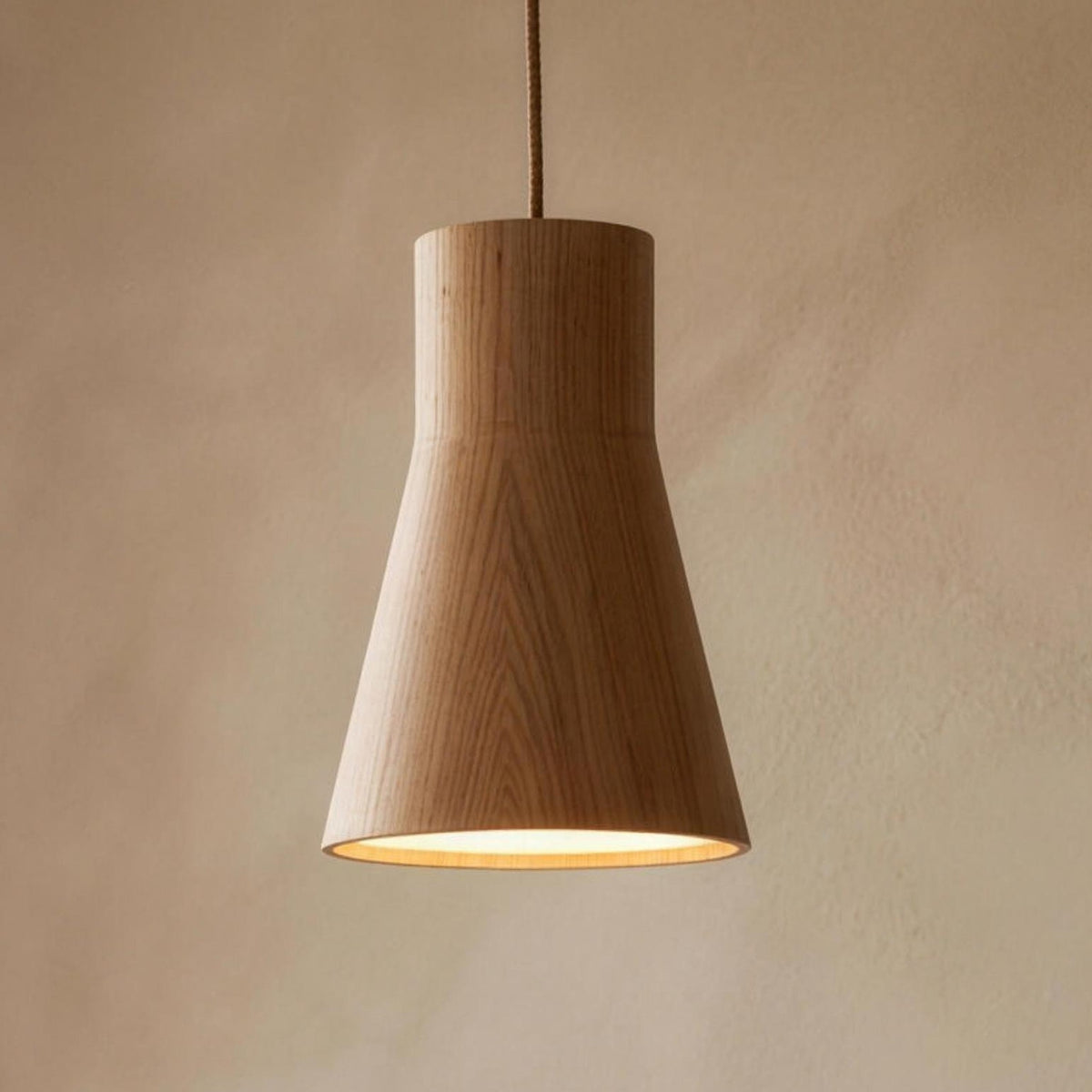 Svea wood pendant light, cone shade in oak, over a round dining table
