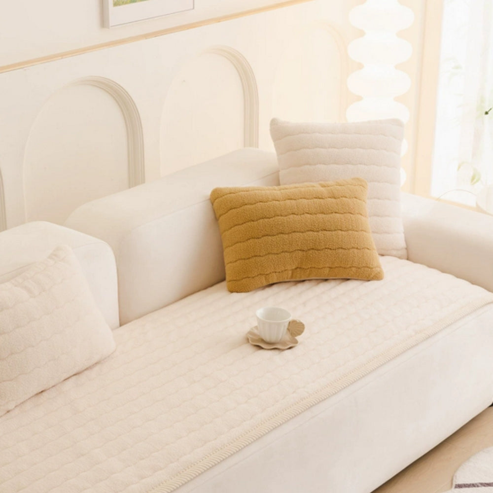 Cream quilted sofa cover on a white sofa with cream and mustard pillows