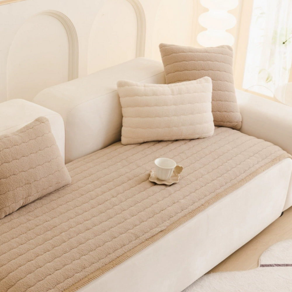 Taupe quilted sofa cover on a white sofa with matching pillows