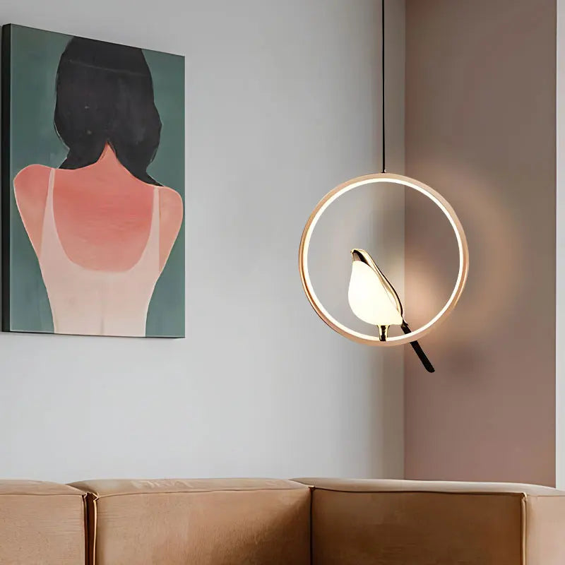 Gold ring bird pendant glowing beside a framed painting above a tan sofa