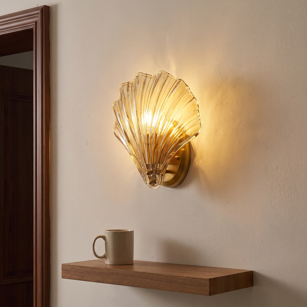 Tyra shell wall sconce lit in a hallway beside a doorway, a mug on a small shelf below