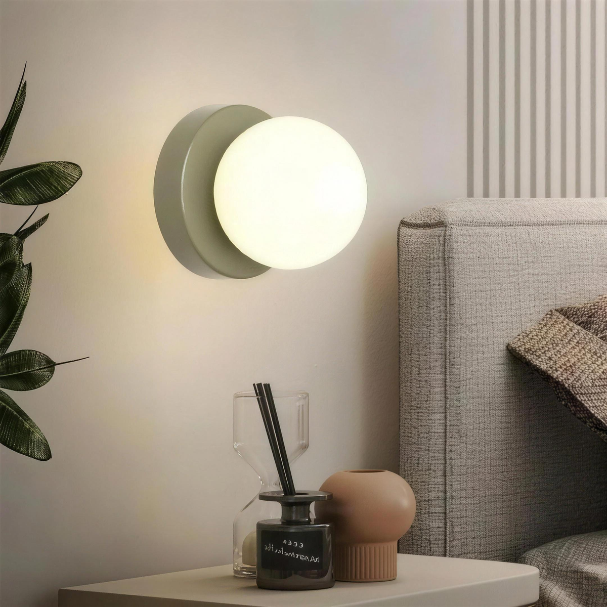 Ulla wall sconce in Green lit beside a bed above a nightstand