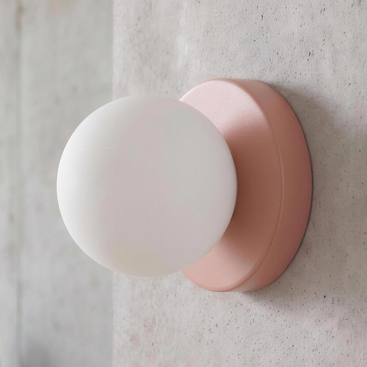 Ulla wall sconce in Pink against a concrete wall